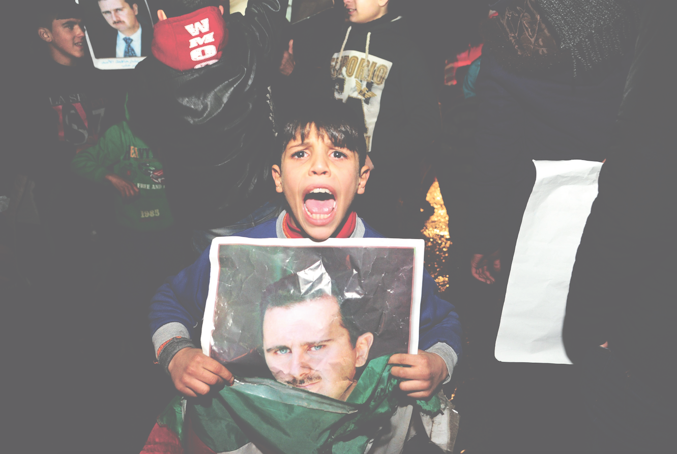 Een jongen met een poster van de Syrische president Assad. – © HH