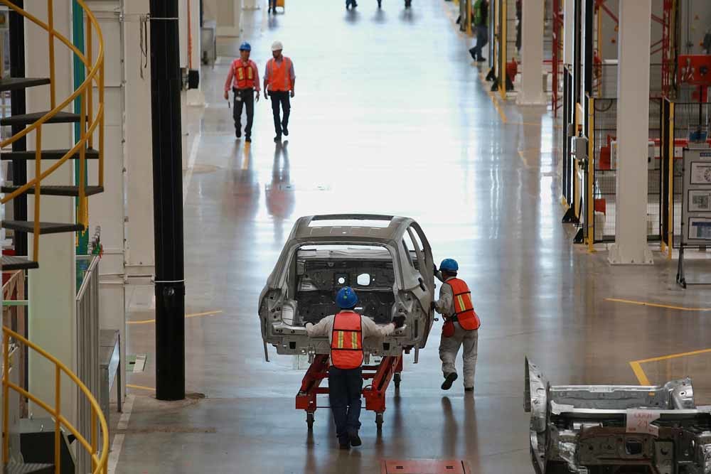 Mexicaanse Volkswagen-medewerkers rijden een chassis door de fabriekshal in Puebla; Een fabriek van Siemens in Berlijn; Het farmaceutische bedrijf B. Brau Melsungen plant een productiefaciliteit in Rusland. – © Bloomberg (1&2) en Photothek via Getty 