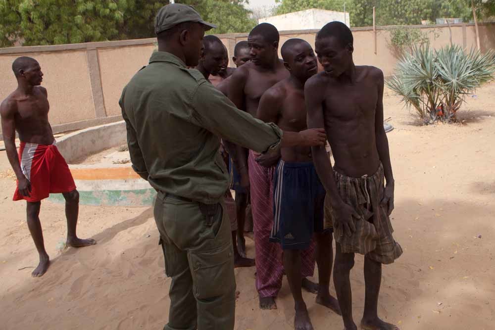 Een Nigeriaanse soldaat met vermoedelijke leden van Boko Haram op de grens van Nigeria en Niger. – © Getty