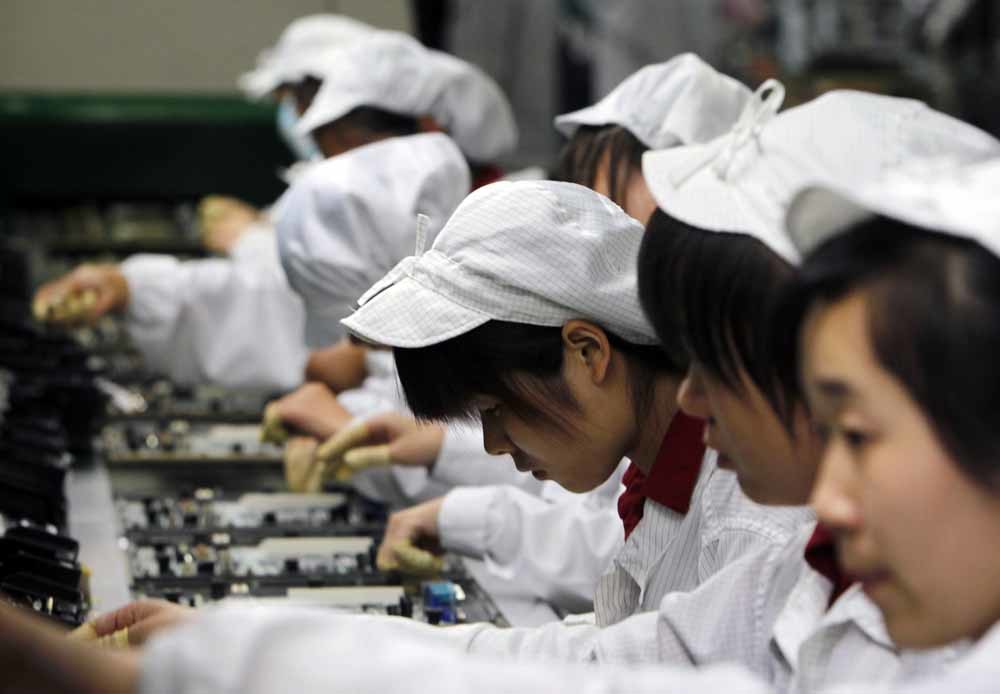 Arbeiders aan de lopende band in het Foxconn complex in Shenzhen, China. – © AP /Kin Cheung