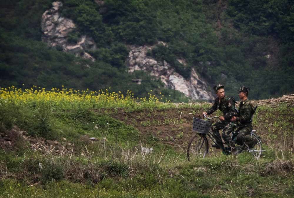Noord-Koreaanse soldaten te fiets bij de Yalu-rivier bij de grens met China. – © Kevin Frayer / Getty