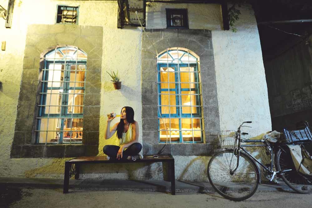 Een studente voor een pub in de oude stad van Damascus. – © Omar Sanadik / Reuters 