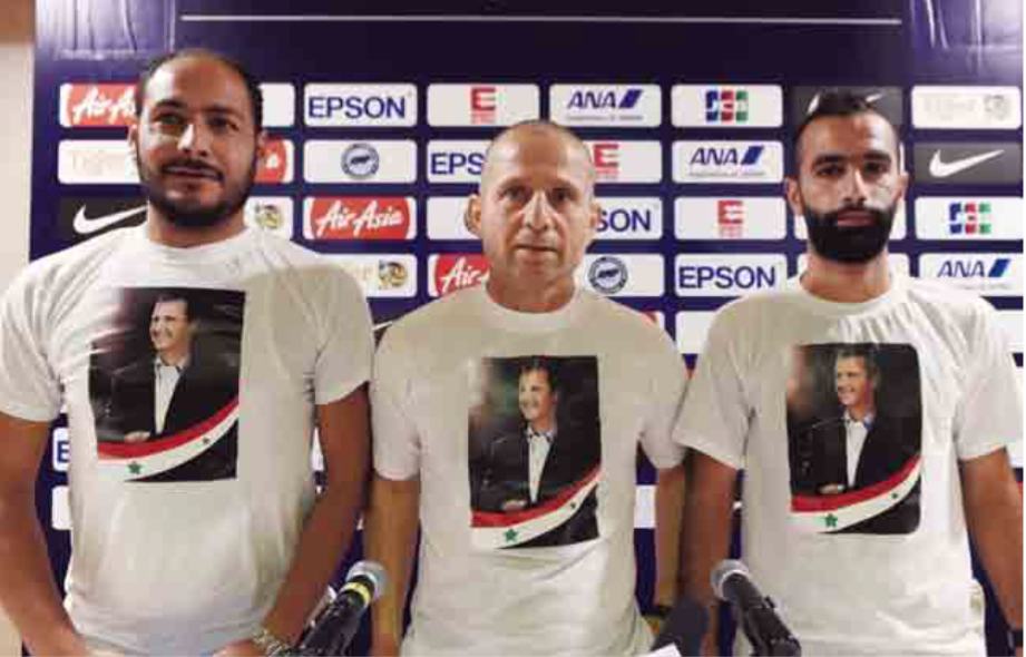De Syrische coach Fajer Ebrahim (m.) draagt een T-shirt met de a eelding van Assad voor de match tegen Singapore in november 2015. – © Roslan Rahman / AFP /Getty Images