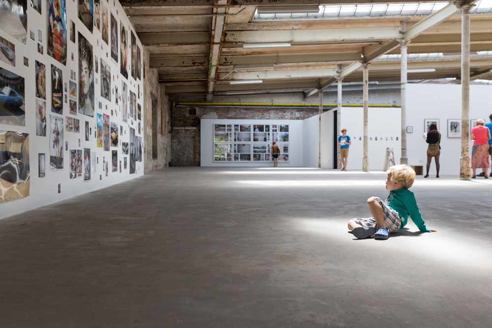 Een jongetje op een fototentoonstelling in een oude fabriek. – © HH