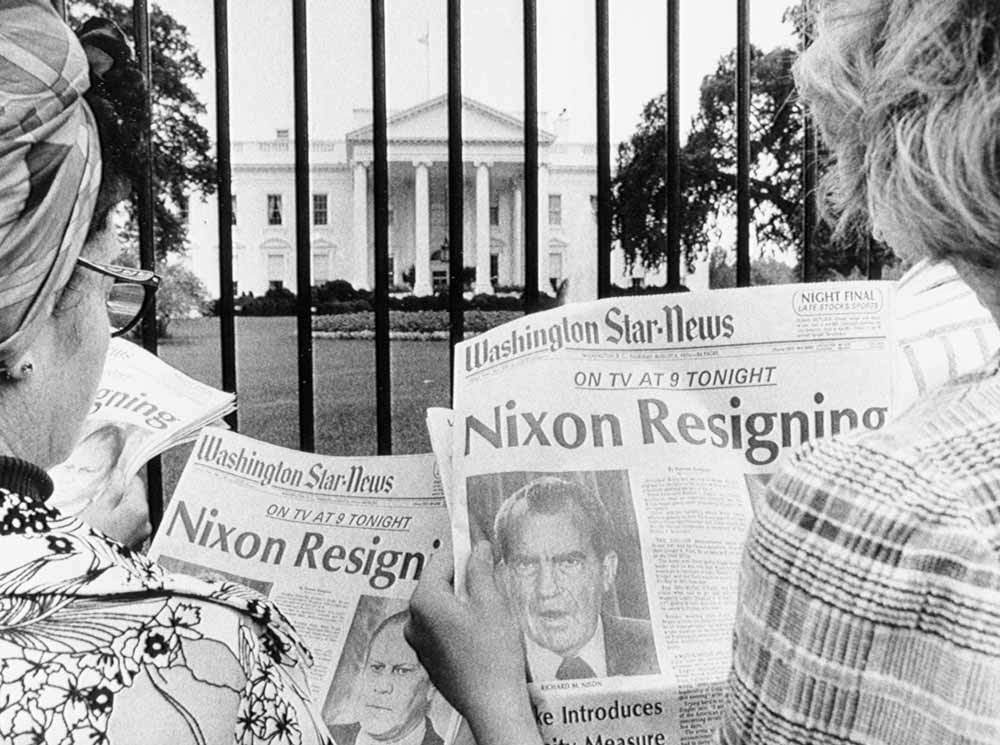 Toeristen bij het Witte Huis lezen het nieuws over het aftreden van de president. – © Getty