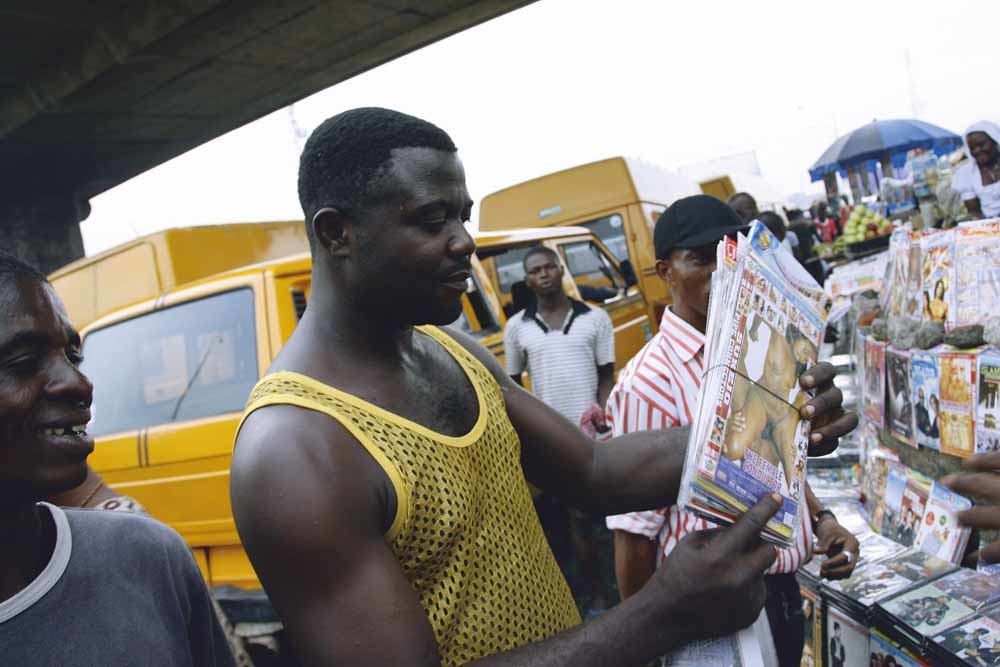 Een man koopt een pornopakket langs de weg in Lagos. In de Nigeriaanse hoofdstad zijn honderden van dit soort stalletjes, die oogluikend worden toegestaan. – © Pius Utomi Ekpei / AFP