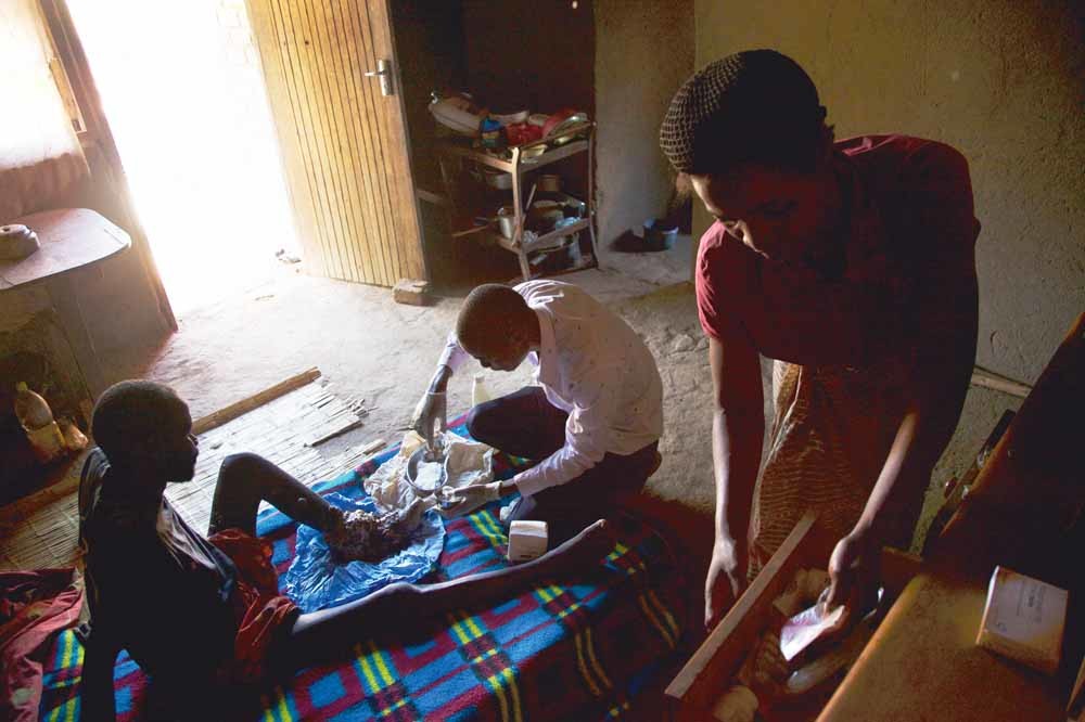 Een medewerker van het Mulanje Mission Hospital in Malawi behandelt een patiënt thuis. – © Kieran Dodds