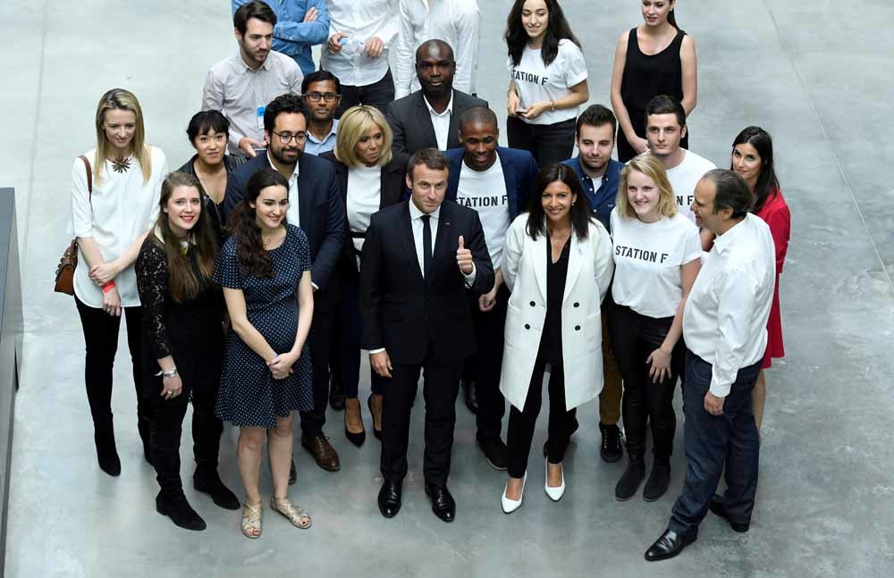 Macron en zijn vrouw met o.a. Xavier Niel (oprichter van Iliad), Delphine Arnault (vicepresident van Louis Vuitton), Anne Hidalgo (burgemeester van Parijs) tijdens de inauguratie van startupincubator Station F in Parijs. – © Bertrand Guay / Reuters