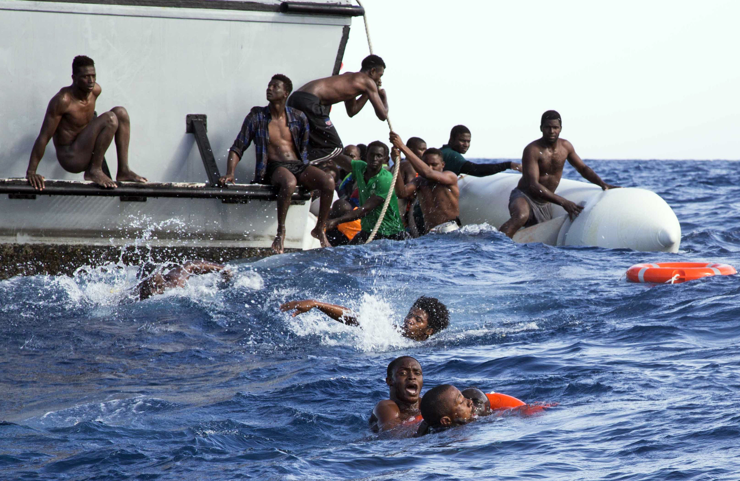 Migranten proberen van een zinkende rubberboot op een boot van de kustwacht van Libië te komen. De foto werd vrijgegeven door hulporganisatie Sea-Watch. – © Lisa Hoffmann / Sea-Watch via AP