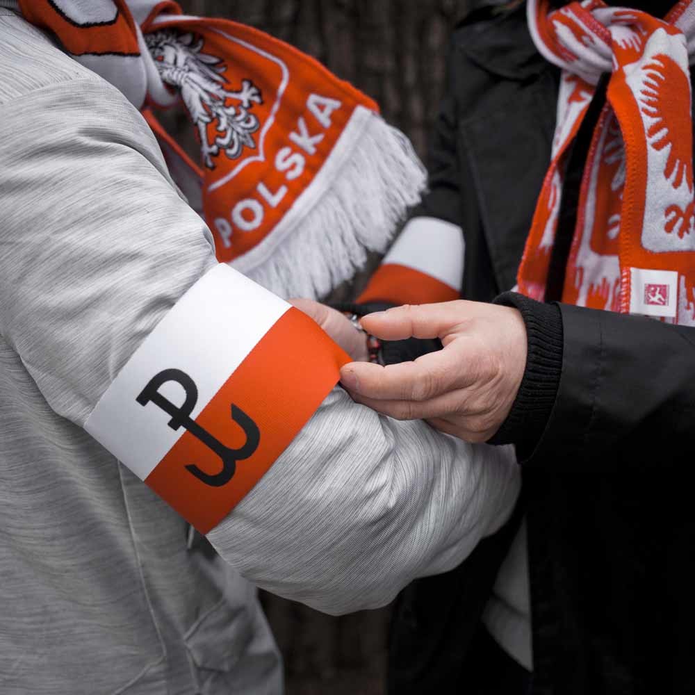 Aanhangers van regeringspartij PiS doen armbanden om bij een demonstratie. – © HH