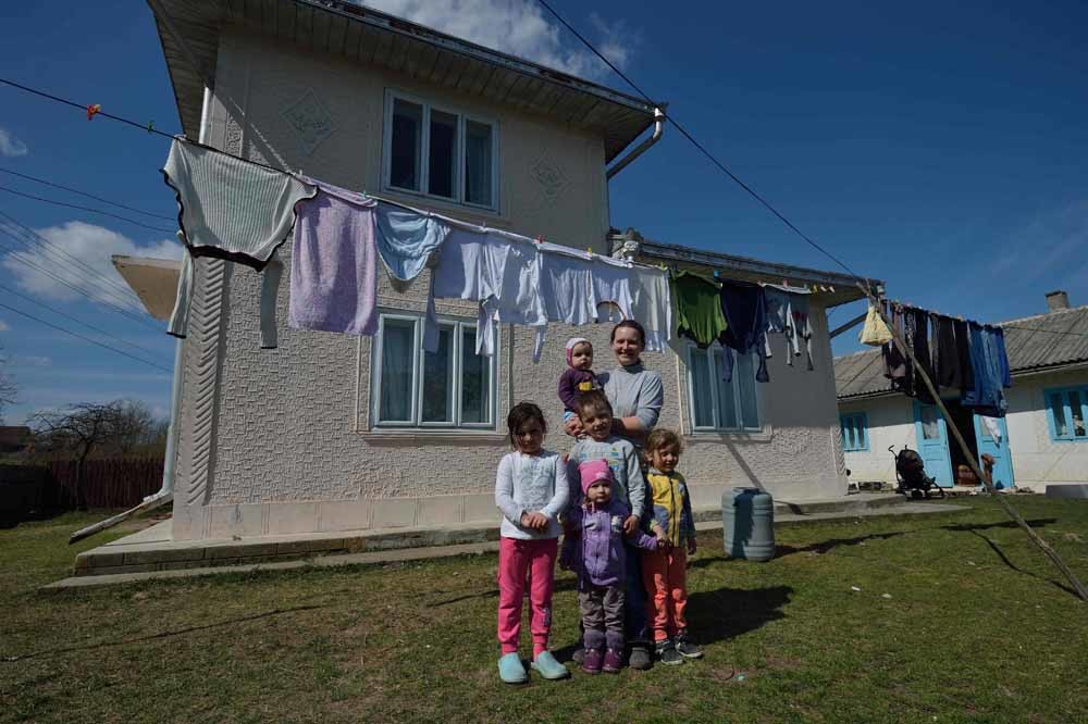 Nieuwe bewoonster Valentina Sotir (42) met vijf van haar acht kinderen voor hun huis in Concesti. Valentina is een alleenstaande moeder die slachtoffer werd van huiselijk geweld. Voor haar was Concesti een uitkomst. – © Daniel Mihailescu / AFP / Getty 