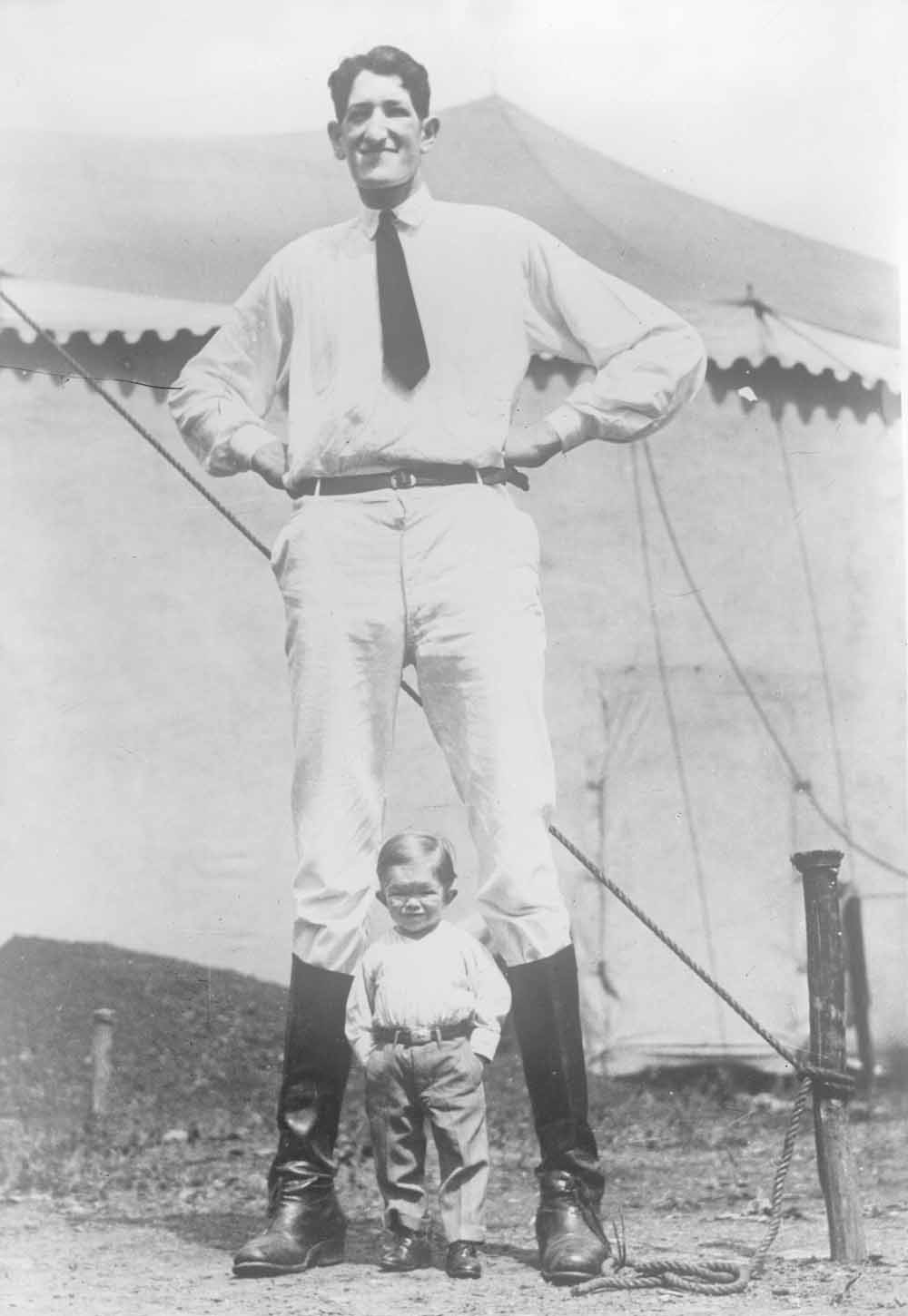 Circa 1930, Jack Earle (2,32 meter), bijgenaamd de ‘Texas Giant’, poseert met iemand die toen een dwerg werd genoemd. Earle werkte jarenlang bij een rondreizend circus en werd later verkoper en fotograaf. – © Getty / Wiki