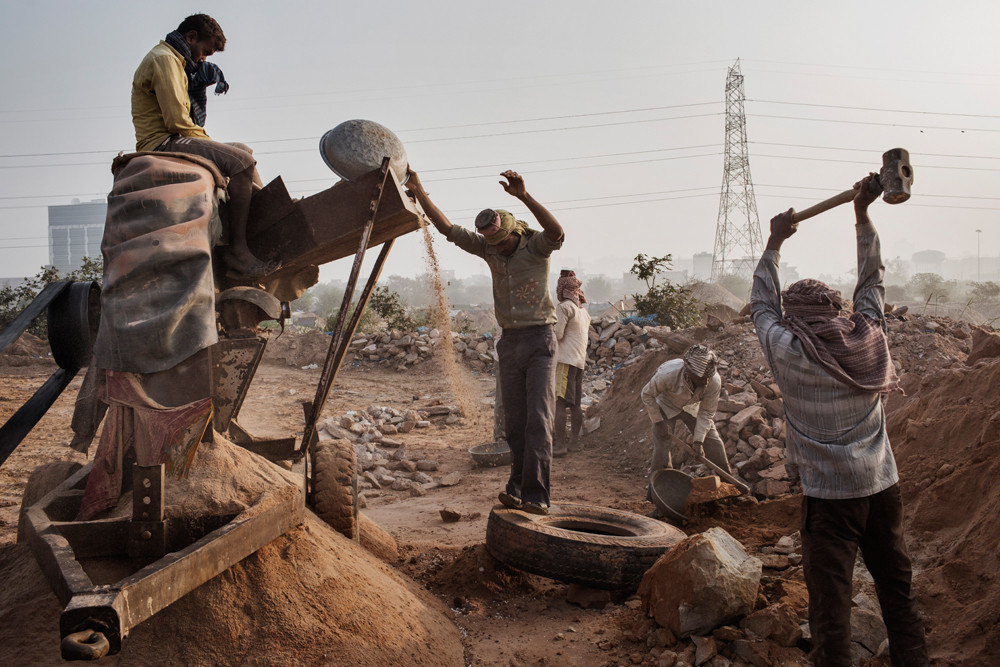 Werklieden slaan stenen fijn tot zand in een illegale mijn bij het dorp Raipur Khadar. – © Adam Ferguson