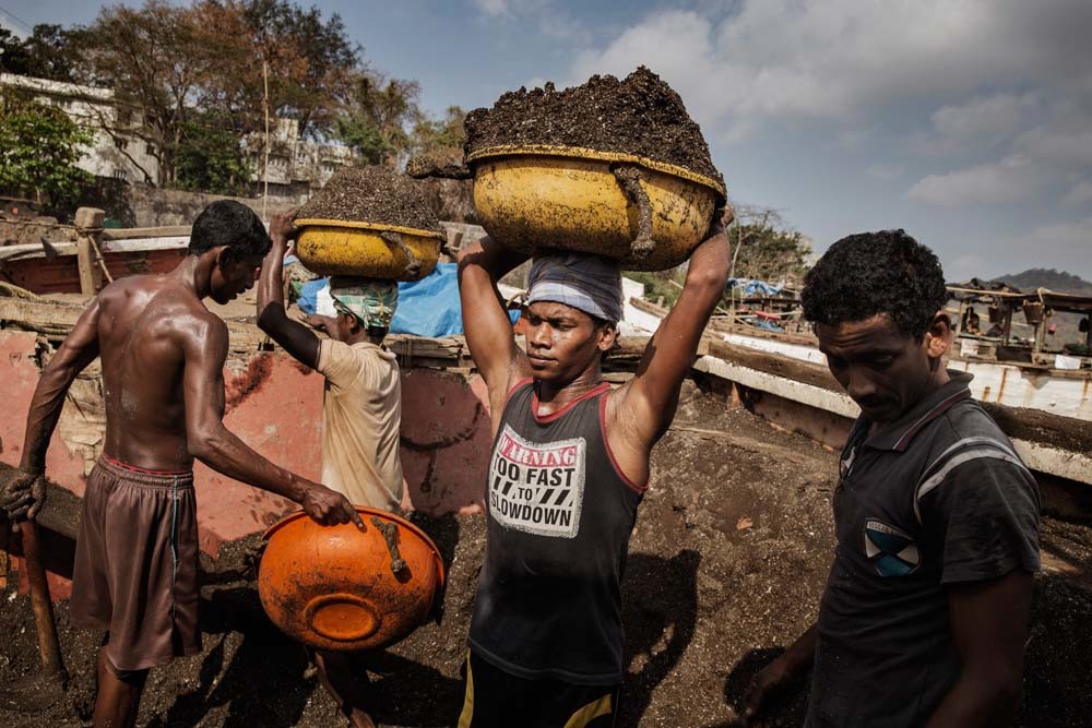 Werklieden uit Bangladesh laden zand uit Indiase boten bij de Thane-rivier bij Mumbai. – © Adam Ferguson