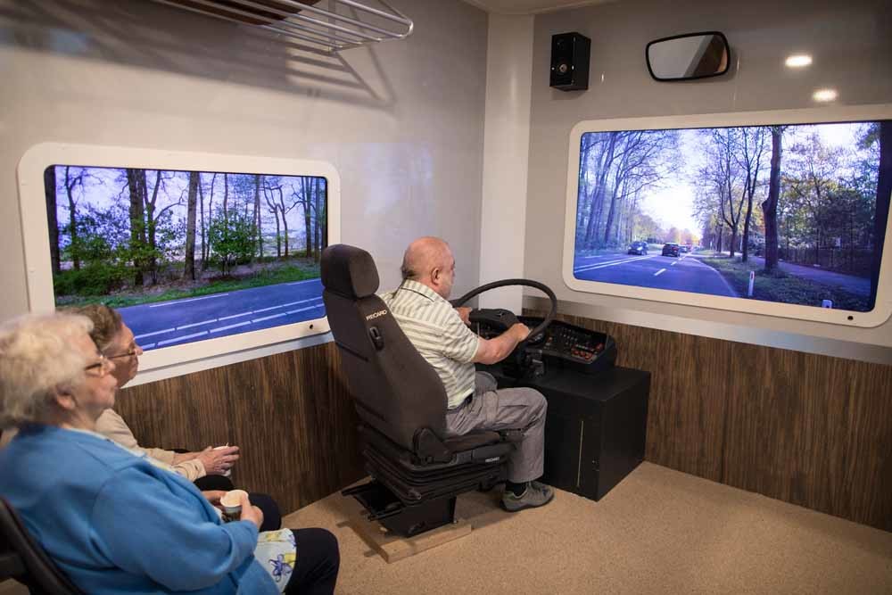 Annie Arendsen, Truus Ooms  en Rudi ten Brink in een nepbus voorzien van videoschermen die de weg tonen in een vertrouwde omgeving.  – © Ilvy Njiokiktjien / The New York Times