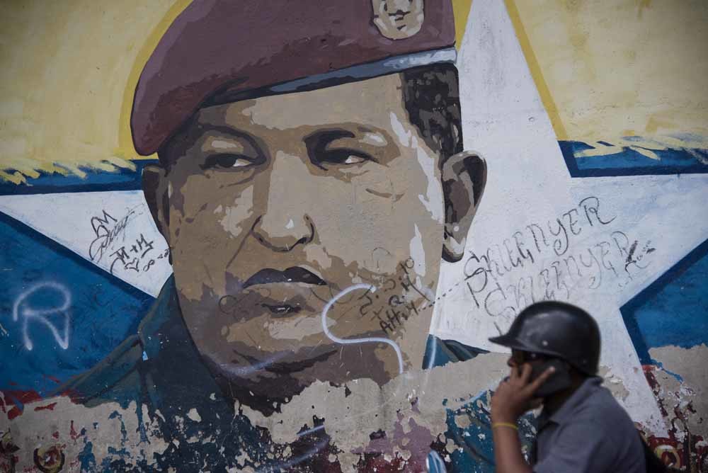 Een voorbijganger belt terwijl hij langs een muurschildering van president Maduro loopt, op zich niks bijzonders maar in Venezuela wel omdat de netwerken worden aangevallen in een poging de overheid te verzwakken.  © Getty