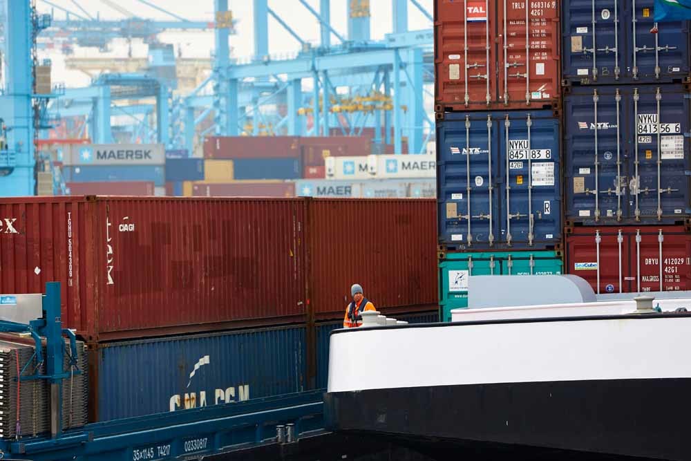 Een vrachtschip met containers wordt de haven van Rotterdam binnengeloodst. – © Getty Images