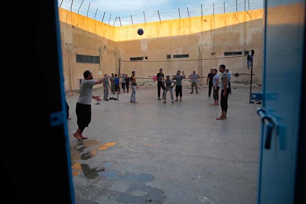 Voormalige IS-strijders spelen volleybal in een Koerdische gevangenis in Noord-Syrië. – © AP Photo / Hussein Malla