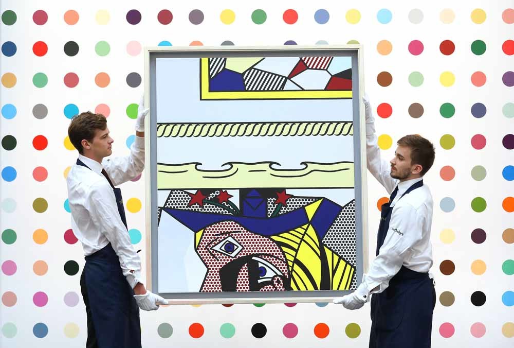 Behoudsmedewerkers dragen het werk Two Paintings with Dado van Roy Lichtenstein. – © Philip Toscano / Getty