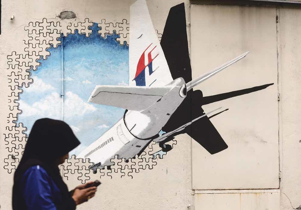 In de Maleisische staat Shah Alam loopt een voetganger voorbij een muurschildering van de MH370. De spoorloze verdwijning sprak nogal tot de verbeelding: het vliegtuig zou geheel intact zijn aangetroffen in de Cambodjaanse jungle, zijn geland in een Indon