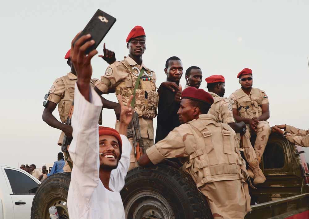 Een man maakt een selfie met de soldaten van het Soedanese leger tijdens een betoging om steun te betuigen aan generaal Mohammed Hamdan Dagalo, vicevoorzitter van de militaire raad, op 15 juni 2019.  © AP Photo / HH