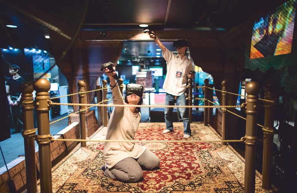 Gamende bezoekers in het Virtual Reality Park in Tokio. Dit pretpark met zeven verschillende virtualrealityspellen is in 2016 geopend in de wijk Shinjuku. De wereldwijde markt voor VR-spellen is hard aan het groeien. – © Tomohiro Ohsumi / Getty Images.