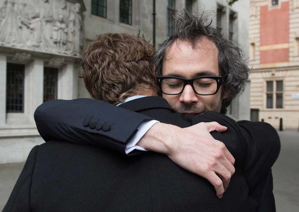James Rhodes (rechts) omhelst zijn jeugdvriend Benedict Cumberbatch nadat een Londense rechter heeft bepaald dat hij zijn boek over seksueel misbruikt mag publiceren. Rhodes' ex-vrouw probeerde de verschijning te laten verbieden omdat de inhoud schadelijk