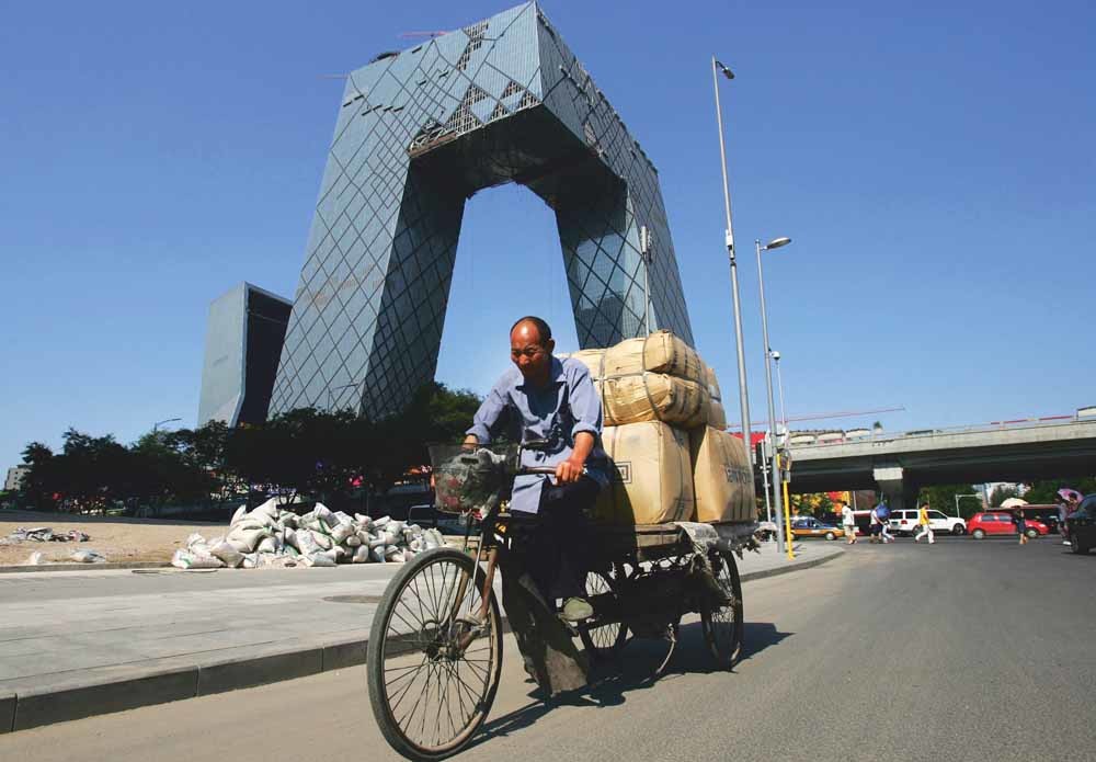 Een man fietst langs het hoofdkantoor van China Central Television (CCTV). – © Feng Li / Getty
