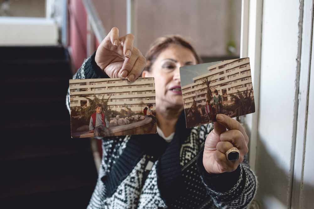 Een bewoonster laat foto’s zien  van appartementencomplex Le Vele di Scampia in Napels, het decor van Roberto Saviano’s boek Gomorra, over de Napolitaanse maffia. – © Ivan Romano / Getty