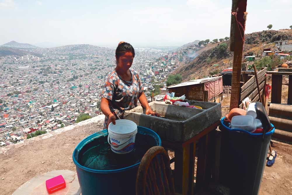Een vrouw in Ecatepec haalt water bij la pipa, een tankwagen die water distribueert in wijken waar dat niet of nauwelijks aanwezig is. – © Reuters / Henry Romero