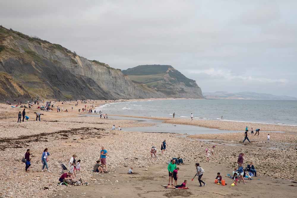 Toeristen en amateur-geologen zoeken naar fossielen op Charmouth Beach in Zuid-Engeland. Deze zogenaamde Jurassic Coast staat op de Werelderfgoedlijst en ligt aan het Kanaal. – © Mike Kemp / In Pictures / Getty