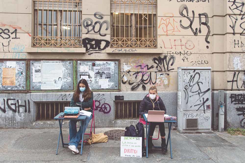 Twee leerlingen in Turijn volgen onlinelessen op de stoep van hun school uit protest tegen de lockdown in Italië. – © Nicolò Campo / Getty