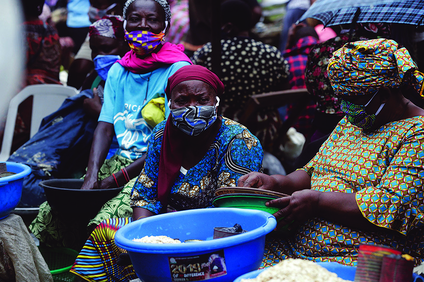 Met zelfgemaakte mondkapjes op de markt in Lagos Nigeria, waar de regels versoepeld werden en het aantal besmettingen steeg. © AP Photo/Sunday Alamba