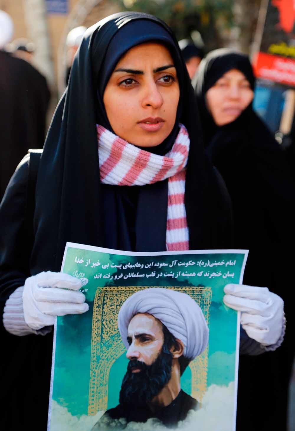 Een Iraanse vrouw houdt een poster omhoog van Nimr Baqir al-Nimr voor de Saoedische ambassade in Teheran. – © Getty