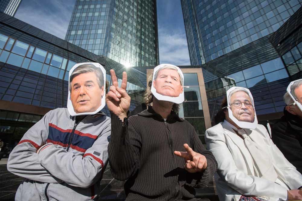 Occupy-activisten demonstreren bij het proces tegen de topmannen van de Deutsche Bank. Ze dragen maskers met de gezichten van bestuurders als Norbert Fitschen, Josef Ackermann en Rolf Breuer. – © HH