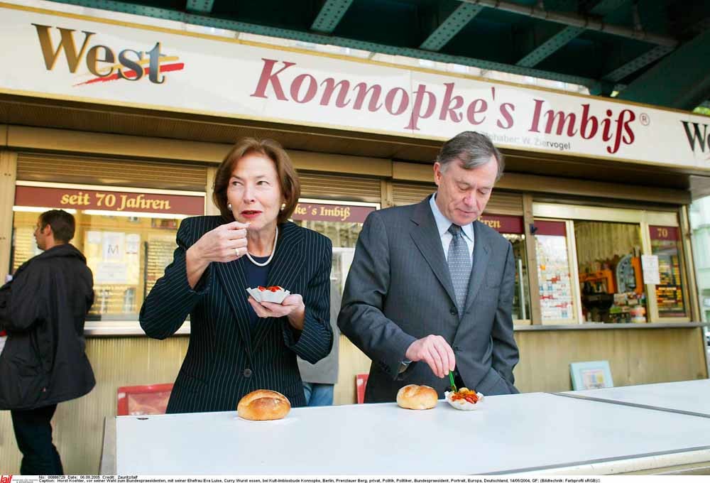 De voormalig Duitse president Horst Köhler en zijn echtgenote Eva Luise eten een broodje curryworst bij de legendarische cafetaria Konnopke in Prenzlauer Berg, Berlijn. – © HH