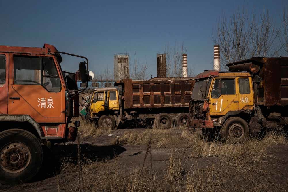 Trucks staan weg te roesten bij de verlaten staalfabriek in Qingquan. – © Kevin Frayer / Getty Images