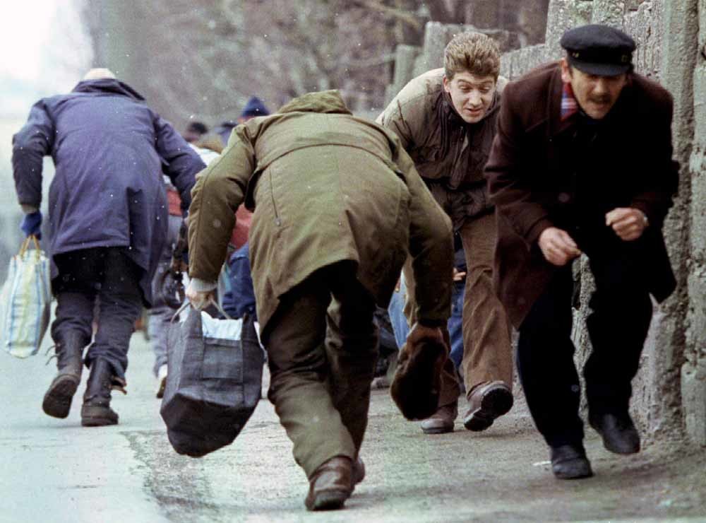 Mensen zoeken beschutting tegen een Servische sniper in de Bosnische hoofdstad Sarajevo, in 1993. Tienduizend mensen vonden de dood gedurende het drie jaar durende beleg van de stad door troepen onder bevel van Ratko Mladic. – © Chris Helgren / Reuters