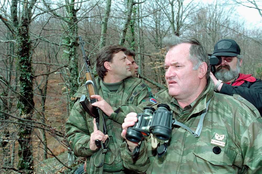 4 x Mladic. 1. Tijdens een belegering in Bosnië en Herzegovina. – © Tomislav Peternek/Polaris; 2. 1993 (l.) en 2011, vlak na zijn arrestatie. – © Reuters; 3. Met Karadzic (r.). – © Didier Ruef/HH; 4. Rechtbank in Belgrado, mei 2011. – © HH