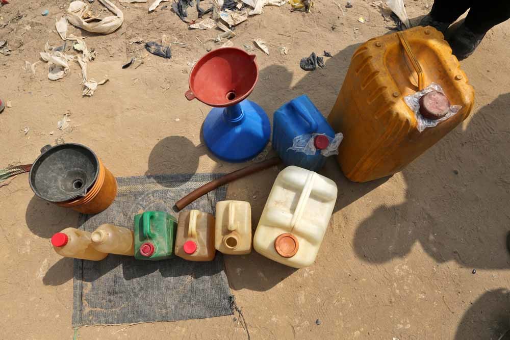 Langs de kant van de weg wordt brandstof verkocht in jerrycans en  essen. – © George Osodi / Getty