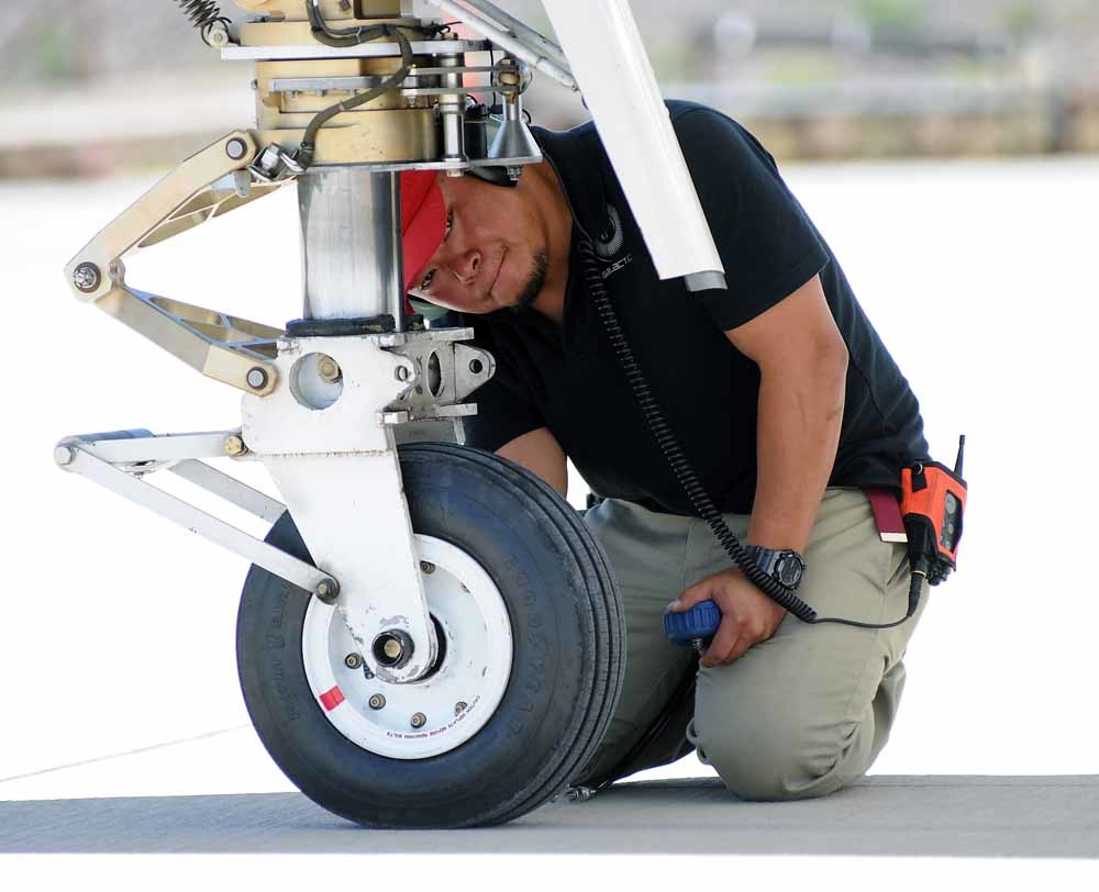 Tee Vong controleert de bandenspanning van de WhiteKnightTwo. – © AP Photo / The Las Cruces Sun-News