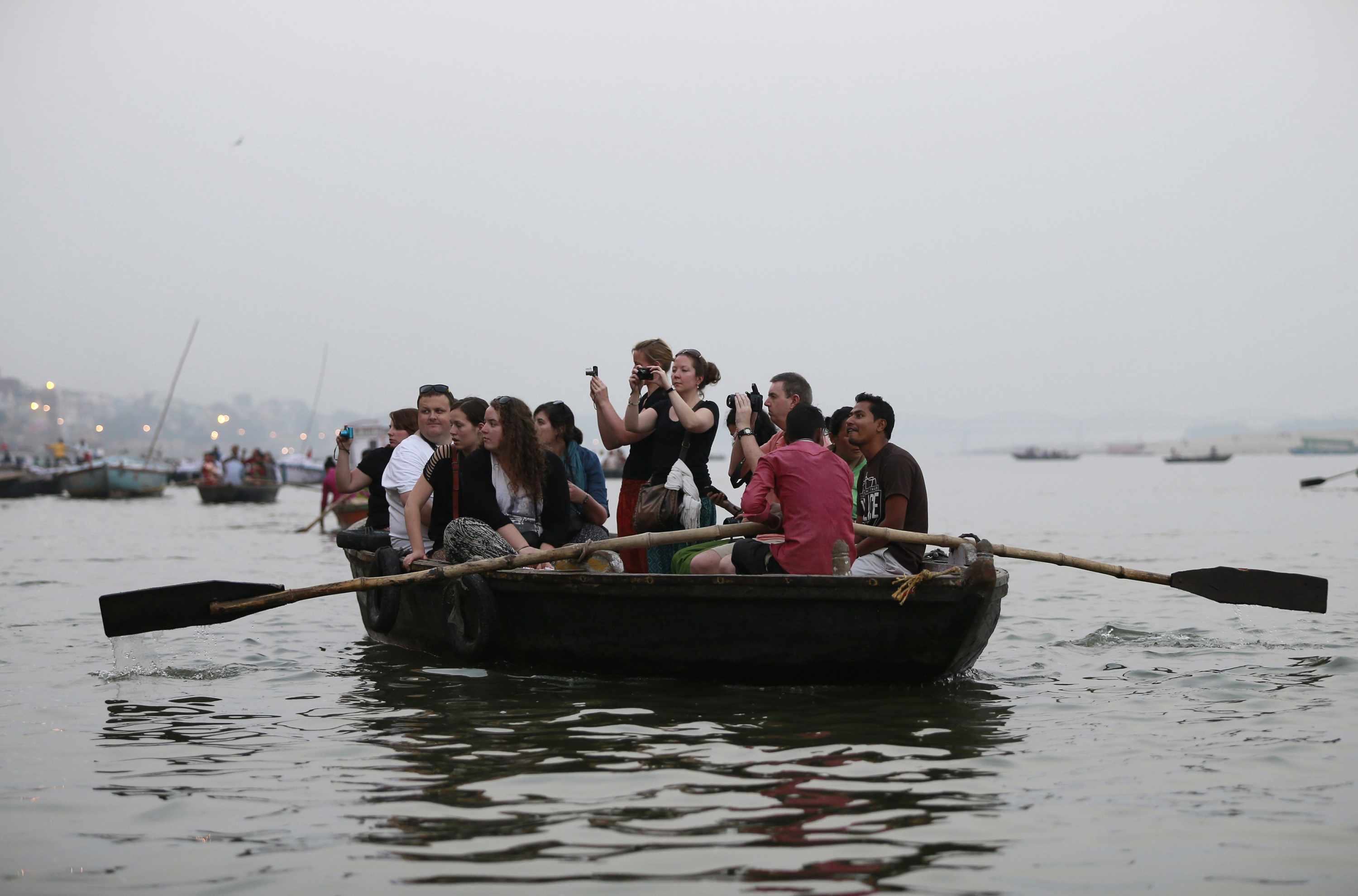 Toeristen schieten plaatjes van badende mensen in de Ganges bij Varanasi. Foto: Reuters