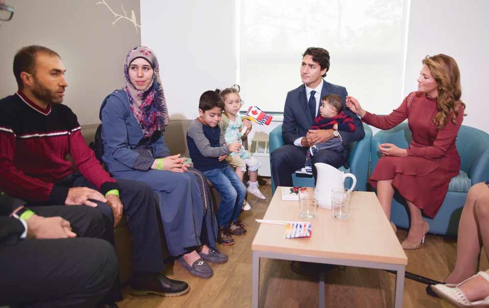 De Canadese premier Justin Trudeau en zijn vrouw met Syrische vluchtelingen in Vancouver. – © Jonathan Hayward / Reuters