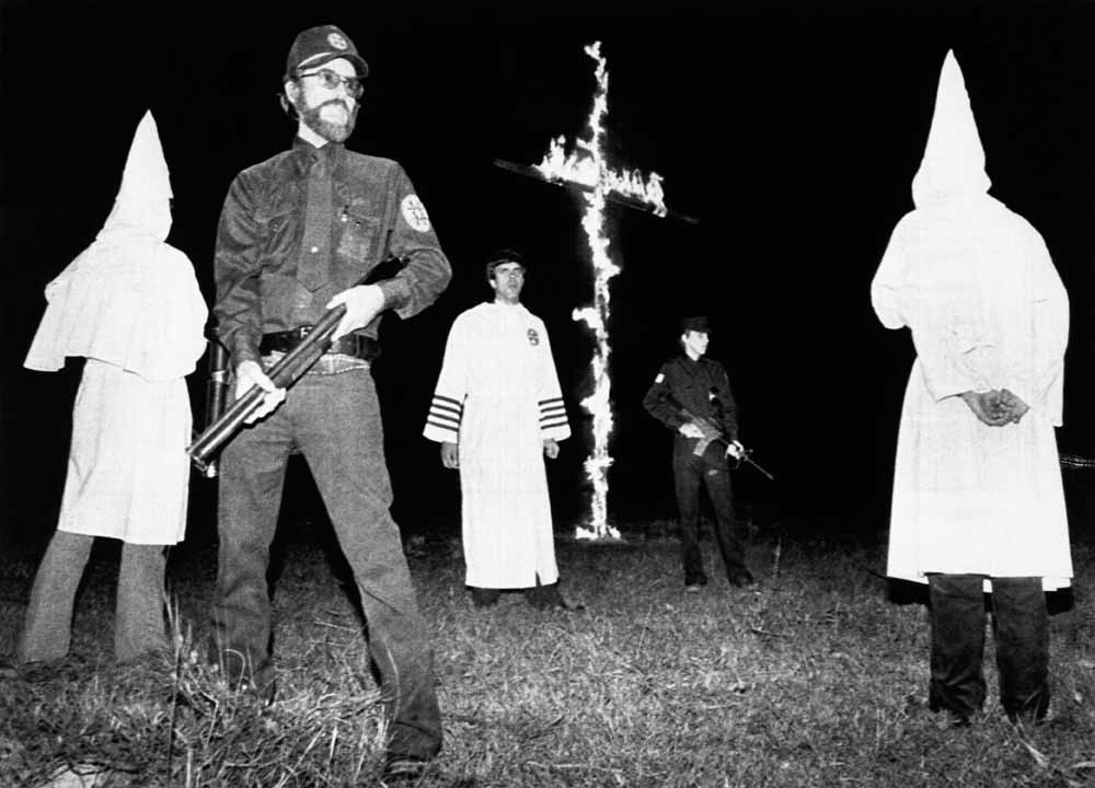 Dereks vader, Don Black, geflankeerd door veiligheidsagenten tijdens een bijeenkomst van de extreem racistische organisatie Ku-Klux-Klan in Winnsboro, Texas. – © Bettmann Archive