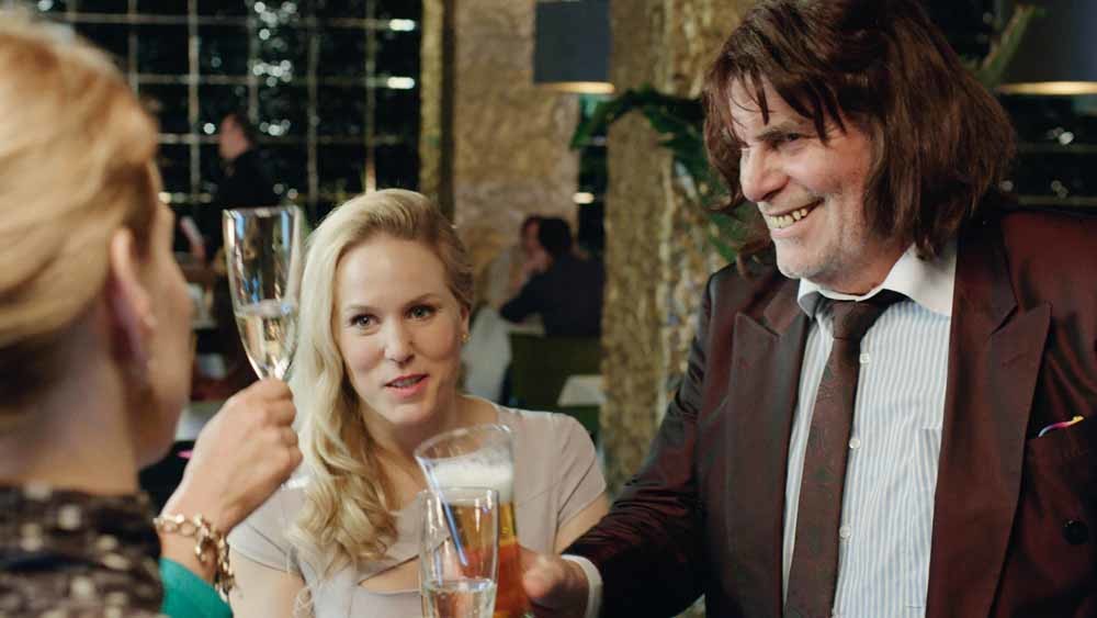 Toni Erdmann (Peter Simonischek) heft het glas met zijn dochter (Sandra Hüller).