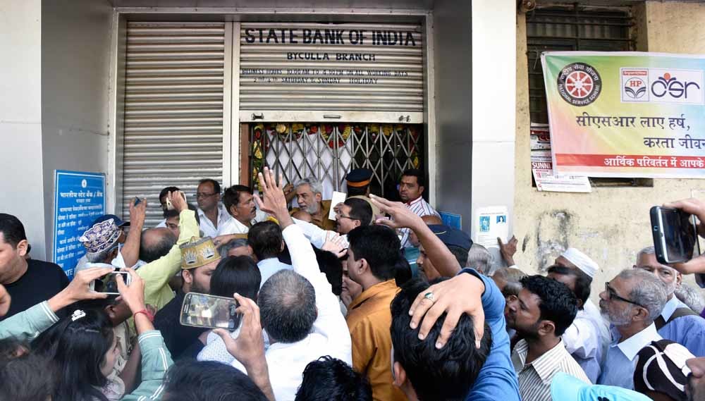 Boze indiërs staan in de rij voor een bankkantoor in Mumbai om hun waardeloos geworden bankbiljetten in te wisselen. – © Kunal Patil / Getty