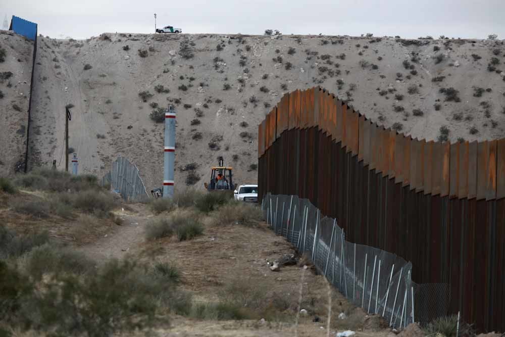 Arbeiders werken aan een hek bij de grens tussen de VS en Mexico. – © HH
